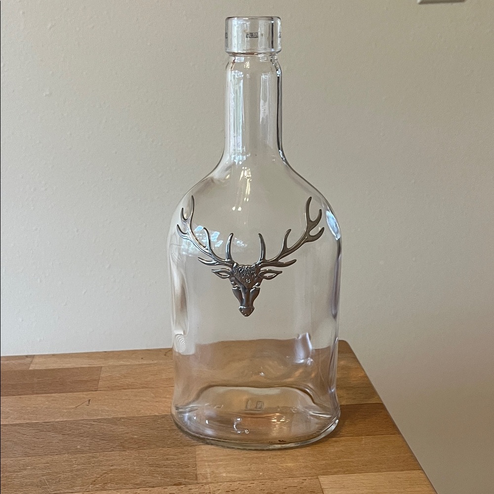 Decorative clear glass bottle with stag design (empty, bottle only).